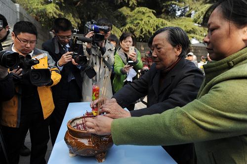 4月4日,南京大屠殺幸存者夏淑琴(右二)和女兒在遇難者名單墻前敬香。新華社記者 韓瑜慶攝