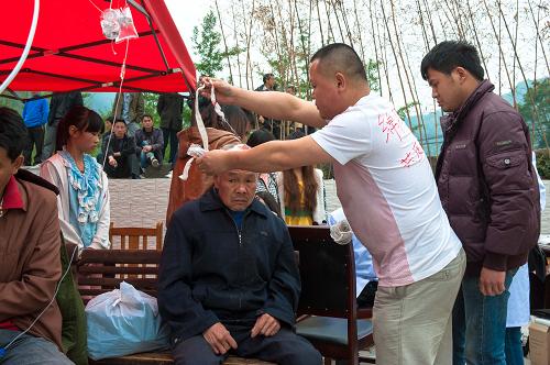 4月21日,志愿者在蘆山縣寶盛鄉(xiāng)為一位受傷老人包扎。新華社記者 陳燮 攝