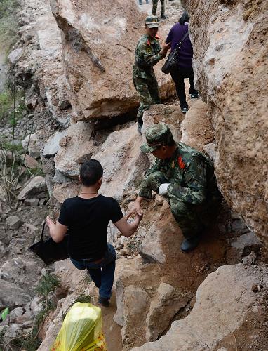 4月21日,受災(zāi)群眾在武警官兵的幫助下沿著損毀的山路前往蘆山縣玉溪村。新華社記者 李橋橋 攝