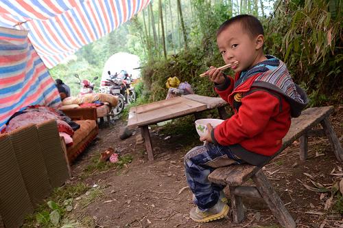 4月21日,太平鎮(zhèn)春光村溪口上組一位小朋友在簡易棚吃午餐。新華社記者 李橋橋 攝