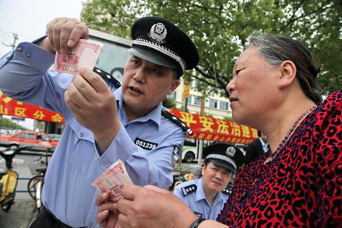 5月15日,上海市金山區(qū)公安分局民警向市民傳授辨別假幣的訣竅。新華社發(fā)(莊毅 攝)