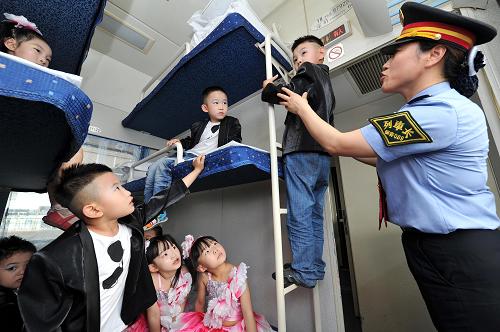 5月27日,在蘭州鐵路局銀川客運段銀川開往北京的K1178次列車上,乘務員向寧夏大學幼兒園的小朋友講解攀爬硬臥車廂內的扶梯時的注意事項。新華社記者 彭昭之 攝
