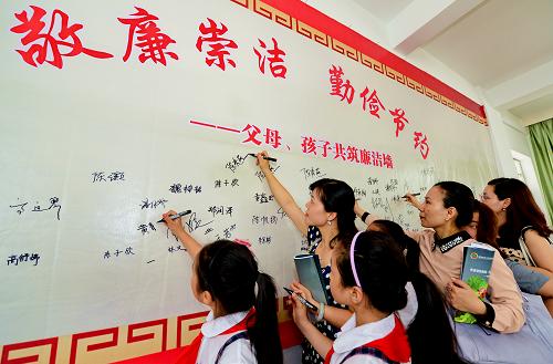5月30日,學生和家長在長樂師范附屬小學舉行的主題中隊會“廉潔墻”上簽名。