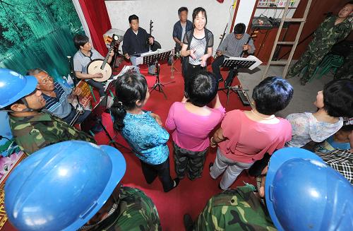 5月30日,在玉田電力公司幫建的宋莊村文化活動(dòng)中心,駐村幫扶的電力職工與村民一起排練表現(xiàn)村民幸福生活的節(jié)目,準(zhǔn)備參加村里“七一”文藝演出。擁有192戶人家的河北省唐山市玉田縣板橋鎮(zhèn)宋莊村是個(gè)滯洪搬遷村,由于歷史及自然條件等原因,宋莊村的發(fā)展相對(duì)滯后。為推動(dòng)宋莊村的新農(nóng)村建設(shè),2012年2月,國(guó)家電網(wǎng)冀北唐山玉田電力公司向宋莊村派出工作隊(duì)駐村幫扶,經(jīng)過一年多的努力,宋莊村舊貌換新顏,村民的經(jīng)濟(jì)收入和幸福指數(shù)不斷提高。一年來,駐村工作隊(duì)共為宋莊村籌措資金近百萬元,幫助村里發(fā)展民營(yíng)企業(yè)、硬化道路,幫助村民建設(shè)文化活動(dòng)中心、農(nóng)家書屋、衛(wèi)生室、文化長(zhǎng)廊,為村里更換老舊變壓器、維修供電線路等,想村民之所想,急村民之所急,被村民親切地稱為“電保姆”。