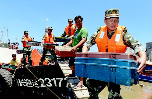 7月12日,福建省長樂市邊防官兵在潭頭鎮(zhèn)福星碼頭幫助漁民轉(zhuǎn)移船上物資。新華社記者 張國俊 攝