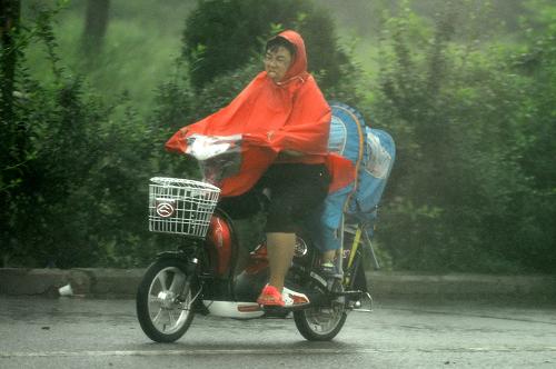 7月23日,在山東省蓬萊市,市民冒雨駕駛電動(dòng)車在道路上行進(jìn)。新華社記者 朱崢 攝