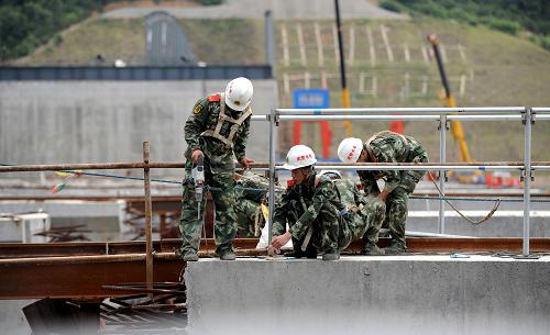 武警水電第二總隊(duì)官兵在峽江水利樞紐工地安裝護(hù)欄(7月27日攝)。新華社記者 周科 攝