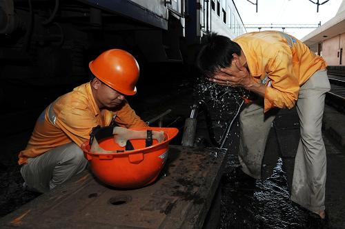 7月27日,45歲的上水工毛劍容(右)和工友在列車上水間隙洗臉解暑。新華社記者 鞠煥宗 攝