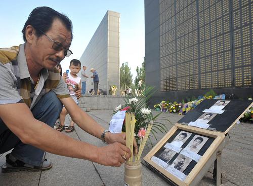 7月28日,一位男士在地震紀(jì)念墻前祭奠逝去的父母和四位兄妹。新華社發(fā)(閆軍 攝)