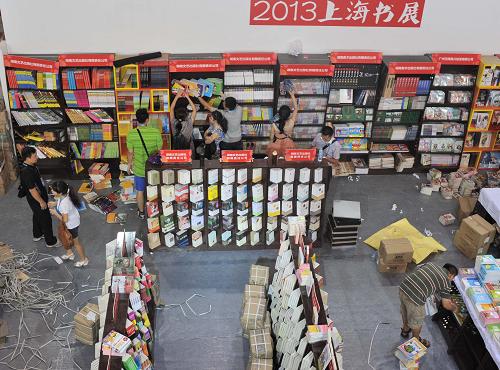 8月13日,在上海書(shū)展一出版社展位,參展工作人員整理書(shū)架。新華社發(fā)(劉曉晶 攝)