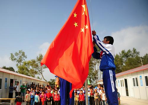 8月25日,在甘肅岷縣永星村,由蘭州軍區(qū)援建的板房學(xué)校——扎扎小學(xué)內(nèi),學(xué)生們舉行升旗儀式。當(dāng)日,該校開始新學(xué)期報(bào)名。新華社記者 張錳 攝