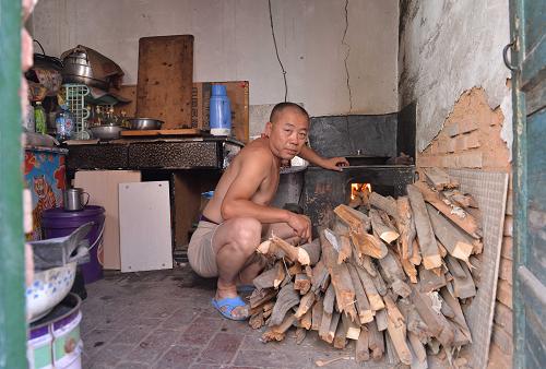 北梁棚戶區(qū)財神廟辦事處紅星社區(qū)49歲的胡建兵正在燒火做飯,胡建兵夫婦和已經(jīng)26歲的兒子目前一起居住在不足20平方米的小屋里(8月21日攝)。新華社記者 任軍川 攝