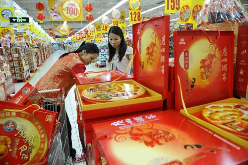 9月4日,超市的促銷(xiāo)人員(左)幫一位消費(fèi)者選購(gòu)月餅禮盒。新華社記者 梁旭 攝