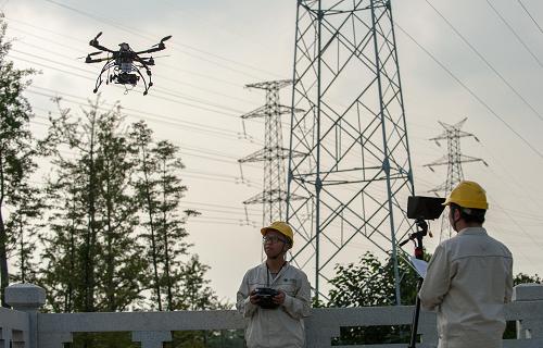 9月28日,國網(wǎng)重慶南岸供電公司輸電線路運維站的兩名電力職工操縱著飛行器進行檢查作業(yè)。新華社記者 劉潺 攝