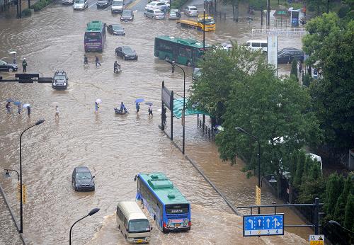 10月8日,積水漫過(guò)杭州市學(xué)院路和天目山路路口。部分車(chē)輛在水中拋錨,行人被迫涉水前行。由于臺(tái)風(fēng)“菲特”影響逐漸減弱,杭州市氣象臺(tái)當(dāng)日14時(shí)20分解除暴雨橙色預(yù)警。但是連續(xù)兩天的強(qiáng)降雨已導(dǎo)致杭州十多處道路路段積水,部分地區(qū)交通受阻,給市民出行和生活帶來(lái)較大影響。新華社記者 鞠煥宗 攝
