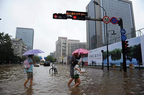 10月8日,行人在杭州市學(xué)院路和天目山路路口涉水前行。新華社記者 鞠煥宗 攝