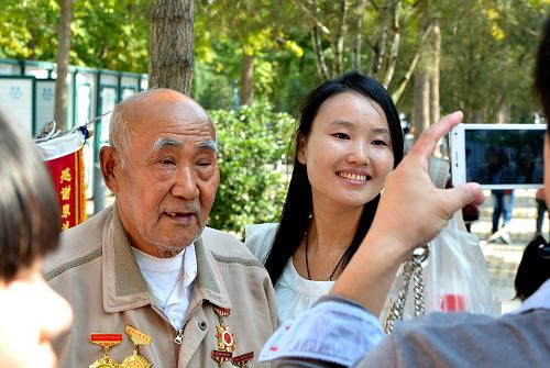 10月13日,一些年輕人在濟(jì)南泉城廣場(chǎng)上和王洪利老人合影留念。新華社記者 馮杰 攝