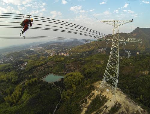 10月30日,浙江省送變電公司的施工人員在50多米高的輸電線路上進(jìn)行巡查。新華社記者 徐昱 攝