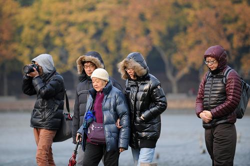 11月27日,幾位游客身著羽絨服在杭州西湖景區(qū)游覽。新華社記者 鞠煥宗 攝