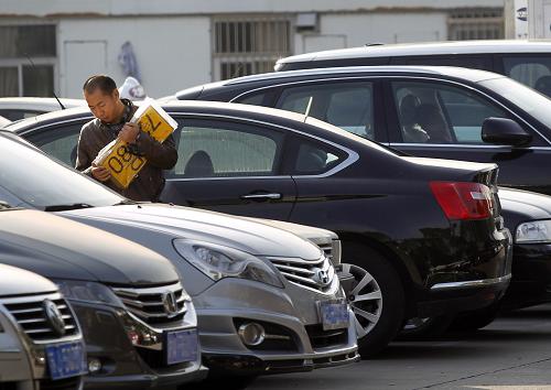 12月11日,一位剛領(lǐng)到滬牌的市民經(jīng)過車管所停車場。新華社發(fā)(丁汀攝)