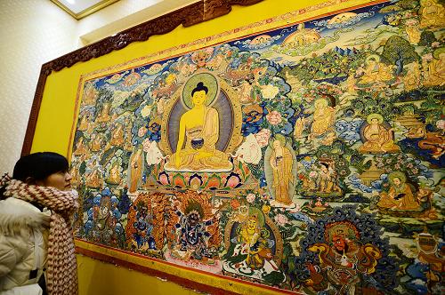 12月17日,在黃南藏族自治州同仁縣龍樹畫院,一名游客在觀賞唐卡作品。近年來,青海省黃南藏族自治州同仁縣大力發(fā)展以唐卡、堆繡、泥塑為主的熱貢藝術(shù)產(chǎn)業(yè),為當(dāng)?shù)?.6萬名藏族群眾及相關(guān)從業(yè)人員開啟了致富路。2013年,當(dāng)?shù)責(zé)嶝曀囆g(shù)產(chǎn)業(yè)收入超過3億元,人均收入超過2萬元。青海省黃南藏族自治州素有“熱貢藝術(shù)之鄉(xiāng)”美譽(yù)。熱貢藝術(shù)是中國藏傳佛教藝術(shù)的重要流派,主要包括唐卡、堆繡、建筑彩畫、酥油花等多種藝術(shù)形式,因發(fā)祥于青海省黃南藏族自治州同仁縣隆務(wù)河畔的熱貢而得名。新華社記者 張宏祥 攝