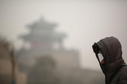 12月24日,游人從河北省邯鄲市被霧霾籠罩的武靈叢臺附近走過。新華社發(fā)(張鵬 攝)