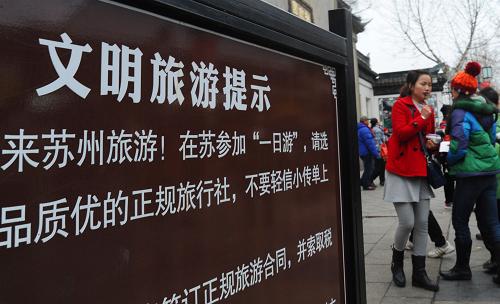 2月3日,一名導(dǎo)游在蘇州拙政園入口處“文明旅游提示”牌前迎候游客。 新華社發(fā)(王建中 攝)