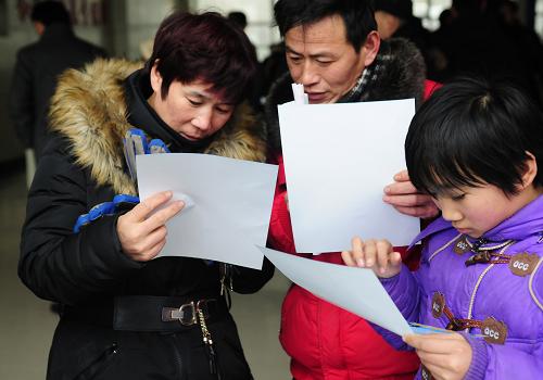 2月5日,在山東省聊城市魯西人力資源公司服務(wù)大廳,來自聊城市陽谷縣郭店屯鄉(xiāng)的劉云廣(中)、洪書平(左)夫婦帶著孩子在查看招聘信息。新華社發(fā)(張振祥 攝)