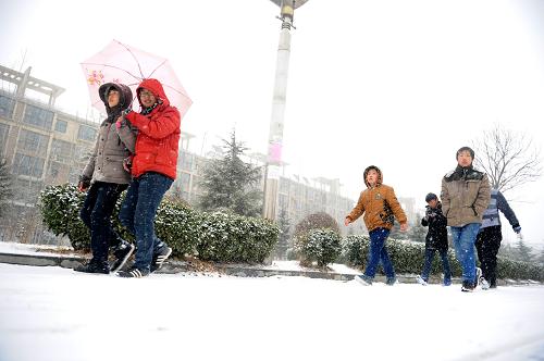 2月5日,在河南省睢縣,幾名路人在雪中前行。新華社記者 劉軍喜 攝