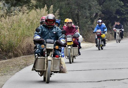 2月15日,返粵務(wù)工人員騎摩托車行駛在207國(guó)道廣西賀州市賀街鎮(zhèn)路段。新華社發(fā)(黃旭胡 攝)