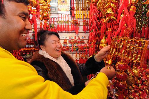 1月16日,印度客商安杰德(左)在義烏小商品市場選購寓意恭喜發(fā)財?shù)?#8220;金算盤”。新華社記者 譚進 攝