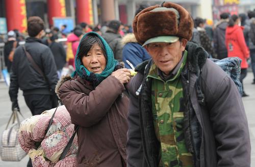 1月26日,兩名背著大包的農(nóng)民工在鄭州火車站準(zhǔn)備回家過年。新華社記者 趙鵬 攝