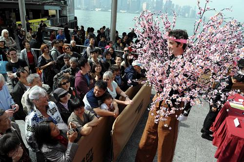 2月6日,腳踩高蹺、身著桃花的“吉祥桃花人”向市民、游客拜年。新華社記者宋振平攝