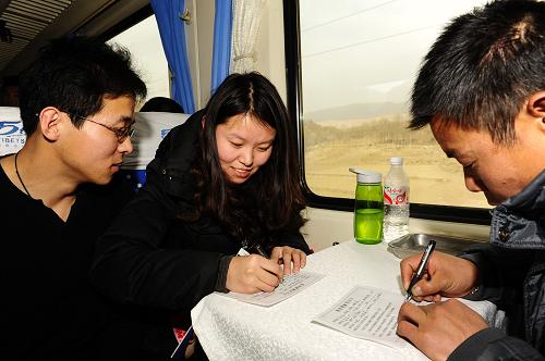 2月6日,乘客程文超(中)在蘭州開往拉薩的K917次列車上填寫健康卡。新華社記者 張宏祥 攝