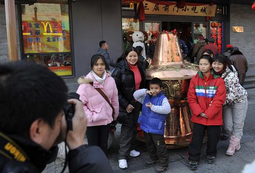 2月17日,幾名游客在北京前門大街東來順飯莊門前的大銅火鍋前留影。新華社記者 魯鵬 攝