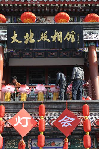 2月17日,幾名工作人員在北京前門大街大北照相館安裝花燈。新華社記者 魯鵬 攝