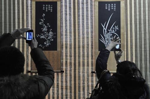 2月17日,兩名游客在“中國(guó)年畫·北京前門首屆作品展”上拍攝展出作品。新華社記者 魯鵬 攝