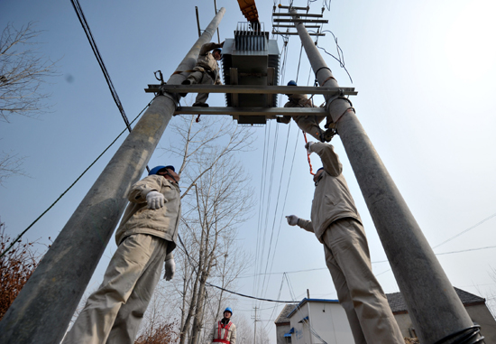 2月23日,安徽省合肥肥西縣高劉鎮(zhèn)江港村內(nèi),電力工作人員正在架設(shè)變壓器裝置,升級(jí)農(nóng)村電網(wǎng)。新華社記者 郭晨 攝