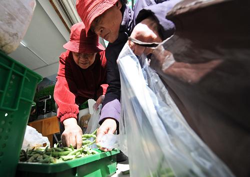 3月15日,在北京海淀區(qū)太平路46號院社區(qū)內(nèi)的“幸福萬壽路便民菜站001號店”,兩位老人在挑選特價扁豆。新華社記者張宇攝