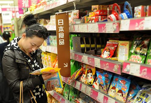 3月27日,一名顧客在青島佳世客超市日本食品專柜查找一包日本糖果的生產(chǎn)日期。新華社記者 李紫恒 攝