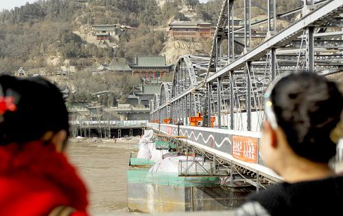 3月27日,兩位蘭州市民在黃河岸邊觀看正在施工的中山橋。新華社記者 高健鈞 攝