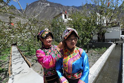 4月15日,理縣木卡鄉(xiāng)木卡村的女孩在為好朋友整理羌繡服飾。新華社記者 何俊昌 攝