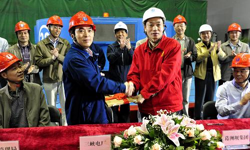 5月24日,在三峽地下電站32號機(jī)組運行交接儀式現(xiàn)場,施工方將首臺機(jī)組的檔案資料移交給電廠運行方。新華社發(fā)(鄭家裕 攝)