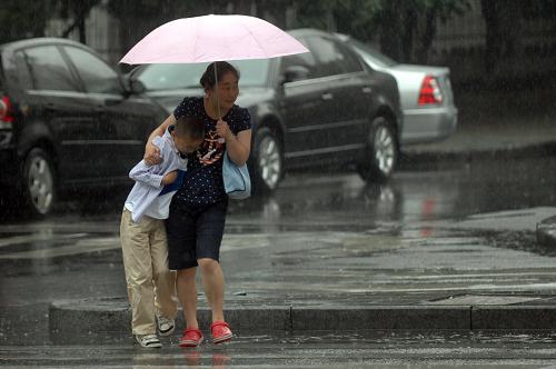 6月4日,杭州迎來大范圍降水天氣,一位行人與兒子一起撐傘過斑馬線。新華社記者 黃宗治 攝