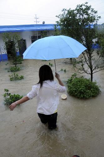 6月15日,一名江西省景德鎮(zhèn)市市民在水中行走。新華社發(fā)(石衛(wèi)明 攝)