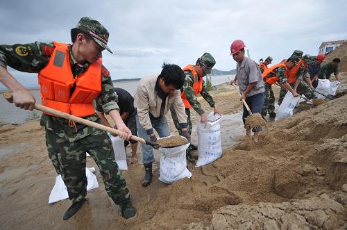 8月5日,浙江臺(tái)州邊防官兵和群眾一起裝沙袋,準(zhǔn)備加固堤壩。新華社發(fā)(郟策 攝)