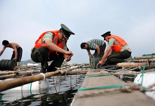 8月7日,煙臺(tái)邊防干警在幫助漁民加固魚(yú)排。新華社發(fā)(臧保東 攝)