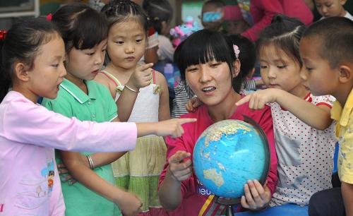 9月1日,陜西省榆林市東升幼兒園學(xué)前班的孩子們在老師封靜(右三)的指導(dǎo)下認識地球儀上祖國的位置。新華社記者陶明攝