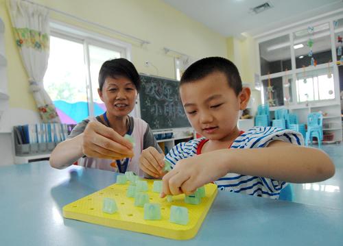 9月1日,在陜西省政府機關(guān)幼兒園,六歲的田霽坤(右)和李存英老師玩數(shù)字游戲。新華社記者 李一博 攝