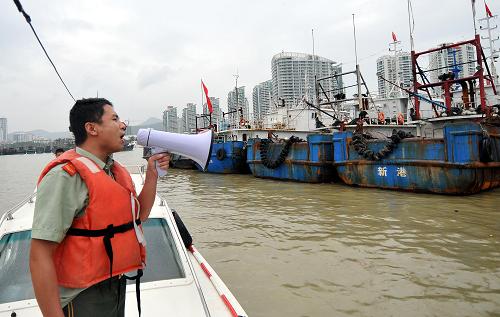 10月3日,海南省公安邊防總隊海警第二支隊?wèi)?zhàn)士在向漁民介紹強(qiáng)熱帶風(fēng)暴“尼格”的信息,提醒漁民注意。新華社記者 侯建森 攝